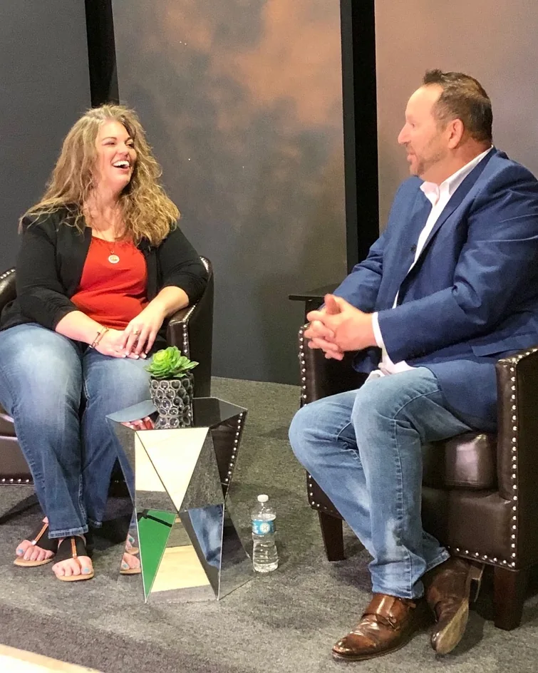 Michael Fineman in conversation with a host on a panel stage, both seated in armchairs